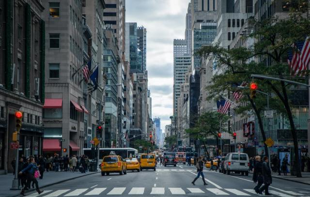 foto de uma rua de nova york, com taxis amarelos e bandeiras dos eua nos prédios