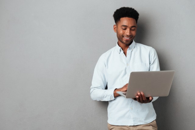 homem em pé segurando notebook aberto