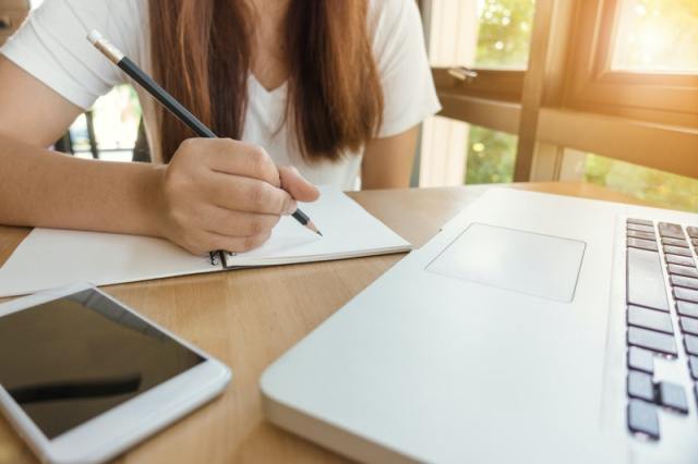 mulher escrevendo em caderno, estudando sobre educação financeira