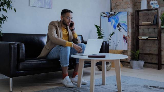 A foto mostra um homem em uma sala, mexendo em um notebook que está sobre uma mesinha de centro, em referência às pesquisas sobre slippage