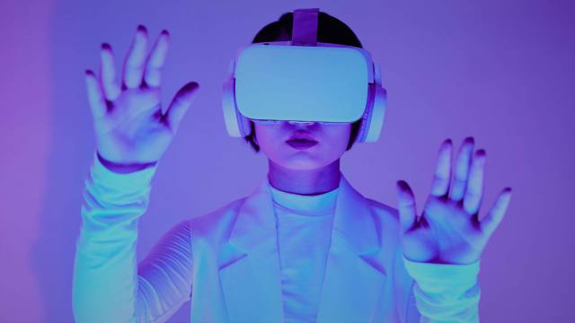 A imagem mostra uma mulher, que veste uma roupa branca, usando um óculos de realidade virtual, que está relacionado a interações por meio de ferramentas de inteligência artificial.