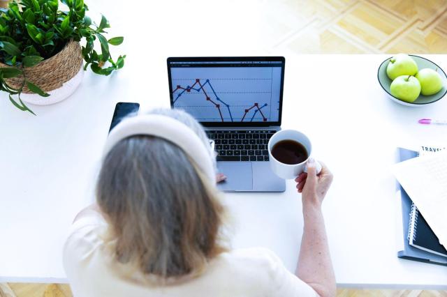 Mulher analisando gráficos financeiros em um notebook para entender como funciona a Bolsa de Valores no Brasil.