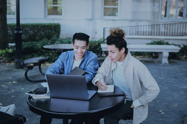 Duas pessoas em uma praça em frente ao computador aprendendo sobre trailing stop com a Clear.